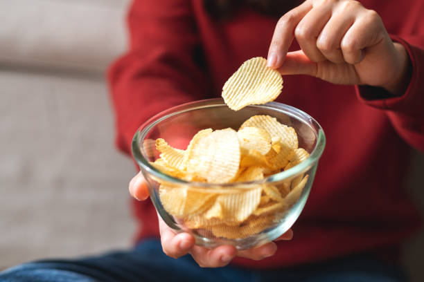 istock a woman picking and eating potato chips at home 1357631292
