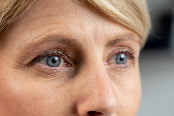 a portrait of a middle-aged woman looks into the distance. close-up of a woman's blue eyes - skin care blue eyes expressing positivity cheerful imagens e fotografias de stock