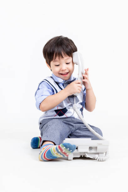 istock little boy play with phone on white background. 1357633524