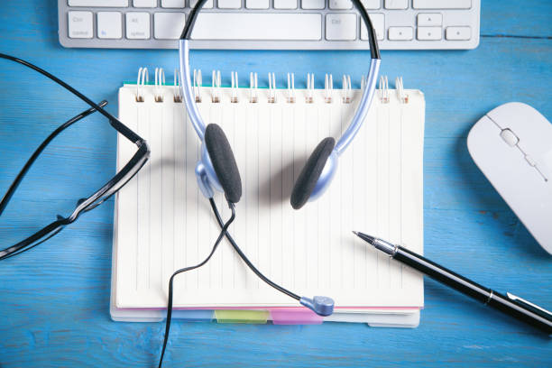 istock Customer service headset, computer keyboard and business objects on the blue background. 1357637075
