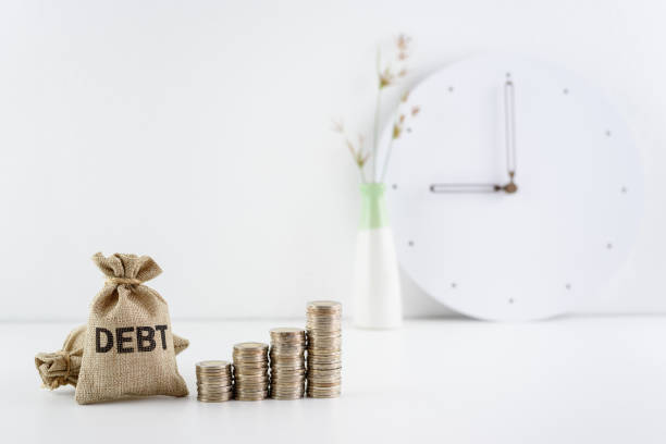 Debt financing, unsecured consumer debt, financial concept : Debt bags and coins on a table, represent the increasing total interest expense a borrower must repay to a lender when making late payment. financiamiento de deuda, deuda de consumo no garantizada, concepto financiero: las bolsas de deuda y las monedas sobre una mesa, representan el creciente gasto total de intereses que un prestatario debe pagar a un prestamista cuando realiza el pago atrasad