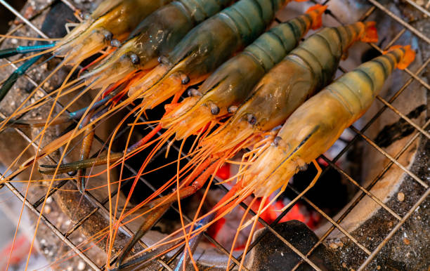 炭火焼きのエビ焼き。巨大な淡水エビは、炎の炭火の上でグリルします。バーベキューグリルラックで巨大な川のエビ料理をクローズアップ。パーティーのために食べ物を調理する。タイの� - shrimp grilled prepared shrimp barbecue ストックフォトと画像