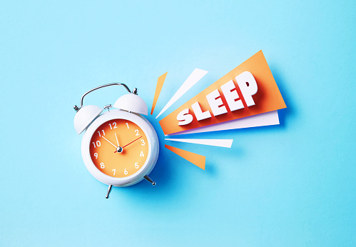 Sleep reads next to white alarm clock on blue background. Horizontal composition with copy space. Bedtime concept.