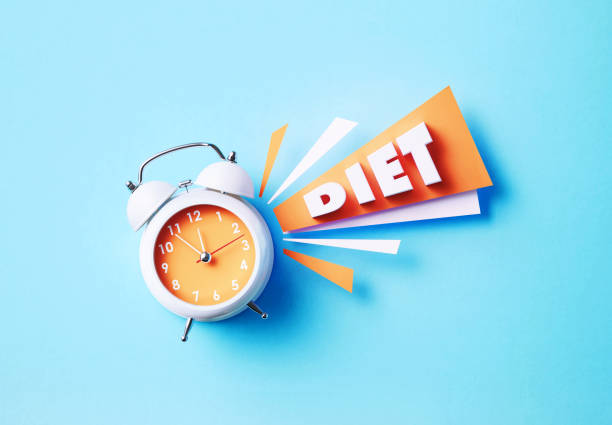istock Diet Reads Next To A White Alarm Clock On Blue Background 1357645858