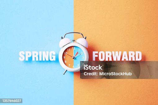 istock Spring Forward Reads Next To A White Alarm Clock On Blue And Salmon Background 1357646027