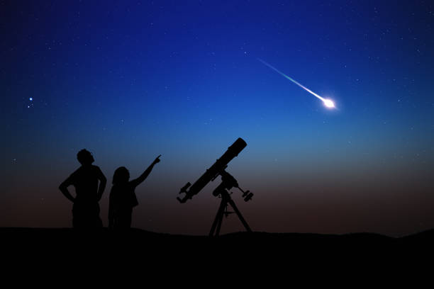 siluetas de padre, hija y telescopio astronómico bajo cielos estrellados. - lluvia de meteoritos fotografías e imágenes de stock