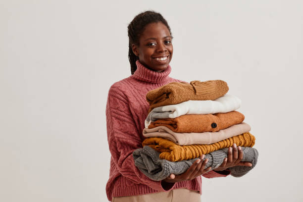 mujer sonriente sosteniendo suéteres - abrigarse fotografías e imágenes de stock