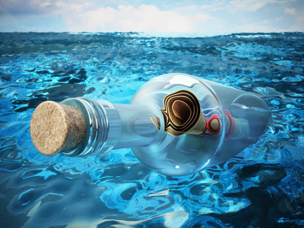 старый свиток с сообщением о помощи внутри стеклянной бутылки, плавающей на воде - stranded message in a bottle island document стоковые фото и изображения