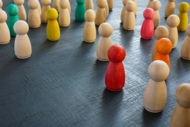 istock Colored figurines among wooden ones. Inclusiveness and uniqueness. 1357648454