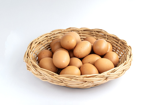 The chicken eggs in basket on white baclgrouns.