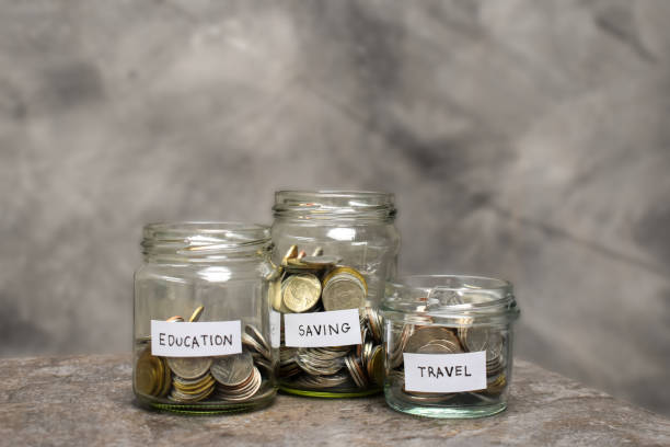 istock Coins in glass jar on marble table. Saving money concept edocation, saving and travel. 1357649694