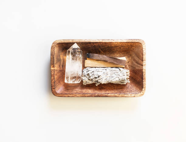 Items for spiritual cleansing - sage bundle, palo santo incense sticks and quartz crystal in wood tray stock photo