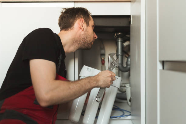 istock Plumber in the kitchen installs a household water treatment system. Three stage flask system 1357653611