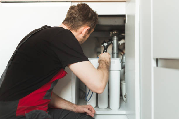 istock Plumber in the kitchen installs a household water treatment system. Three stage flask system 1357653616