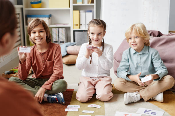 Children playing in English game Group of happy children sitting on the floor and playing in English game together with teacher in the classroom teacher classroom child education stock pictures, royalty-free photos & images
