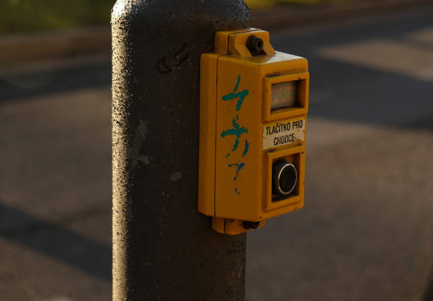 istock Crosswalk button for pedestrian with light warning. Defocused background with Cars drive along road and bokeh from headlights. The inscription in Czech -Tlačítko pro chodce- Button for pedestrians. 1357655204