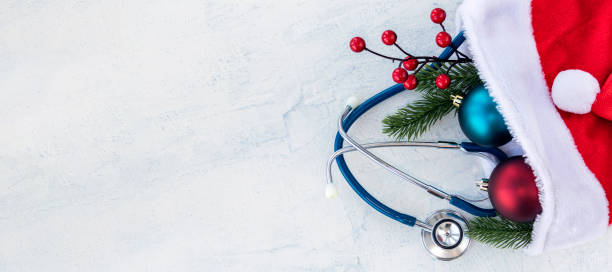 banner with Stethoscope with branches of Christmas tree and Christmas balls in Santa Claus hat. All on a white concrete table. Concept Merry Christmas and Happy New year or Healthy New Year. Copy space. stock photo