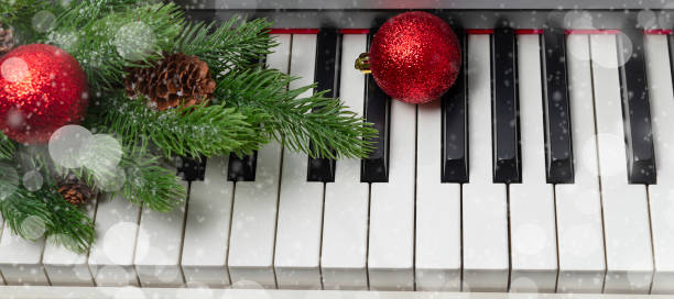 banner with New Year or Christmas music concept. piano with a branch of a Christmas tree, pine cones and red Christmas balls. stock photo