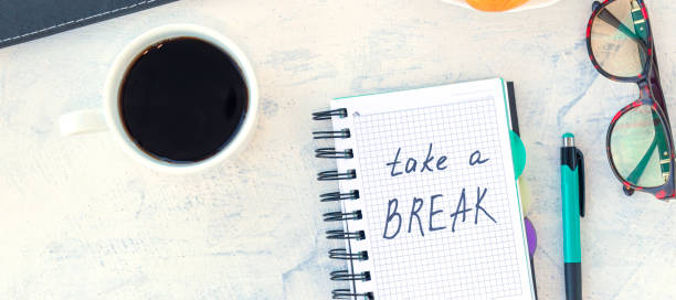 istock banner with Take a break. Concept time off. Words Take a break in a notebook on the working table with cup of coffee and bun. 1357655686