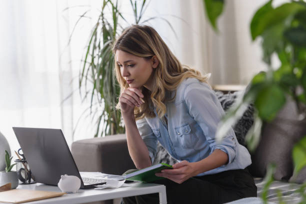 istock Young beautiful woman working on a computer at home, calculating monthly exspences, doing home budgeting 1357657099
