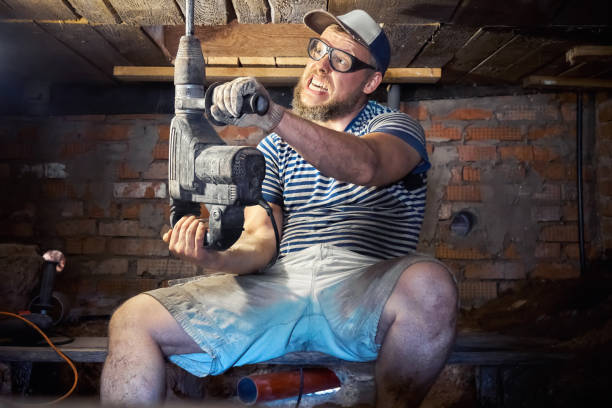 homem barbudo engraçado com perforator de serviço pesado no porão da casa - home improvement work tool hammer portrait - fotografias e filmes do acervo