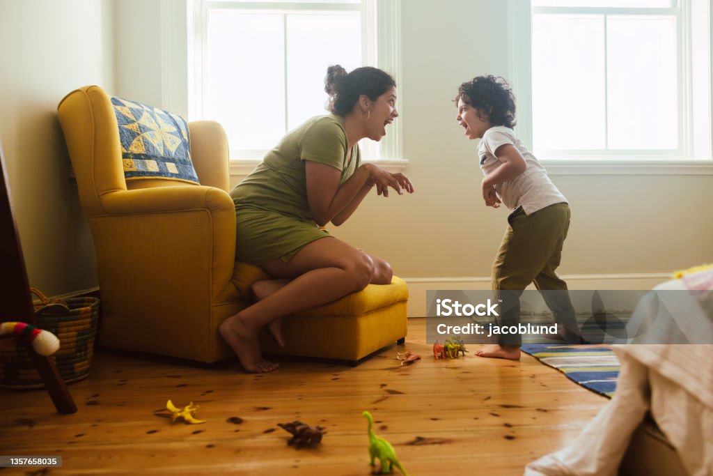 Mother and son imitating a dinosaur at home Mother and son imitating a dinosaur in their play area. Happy mother and son having fun together during playtime. Loving single mother spending some quality time with her son at home. Child Stock Photo