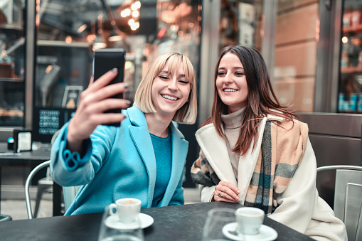 Smiling Female Friends Taking Cute Coffee Time Selfie In Outdoor Bar