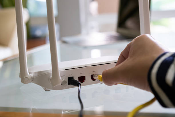 istock Selective focus at Lan cable socket of the router with people hand plug the fiber cable into internet router.  High speed internet for personal use with computer and technology. 1357659873