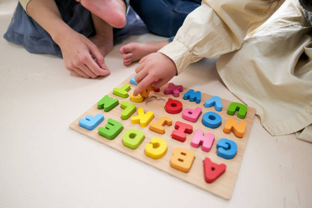 nahaufnahme der hände des kindes beim spielen mit alphabet-spielzeugblock - english game stock-fotos und bilder