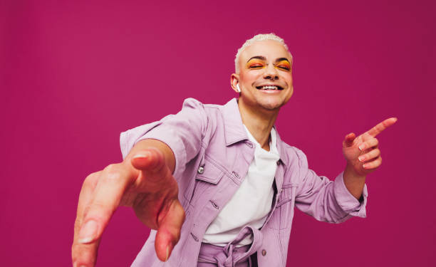 That's my favourite song That's my favourite song. Happy young man dancing to his favourite music while wearing wireless earphones. Queer man smiling cheerfully while standing against a purple background. generation z stock pictures, royalty-free photos & images