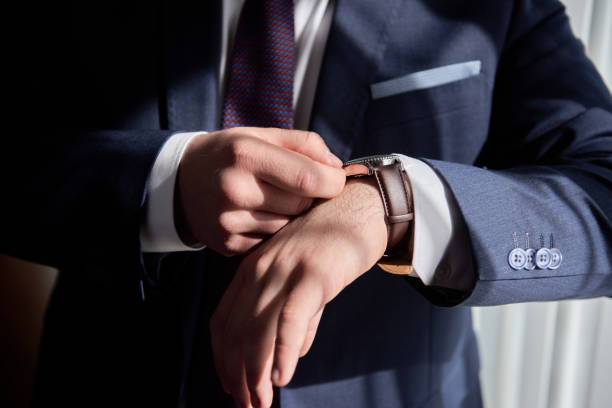 Close up of watches on male hand indoors, copy space. Man in suit checking time from luxury wristwatches. Watch on hand. Groom wedding preparation stock photo