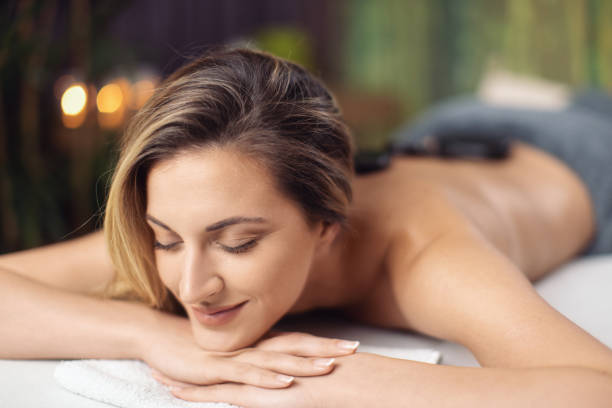 jeune femme séduisante recevant un massage relaxant du dos - massaging spa treatment stone massage therapist photos et images de collection