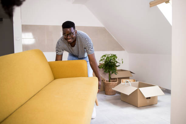 istock Happy African American carrying a sofa while moving into a new house 1357661197