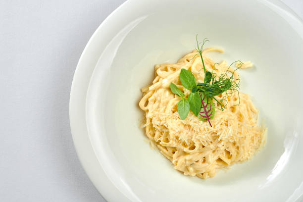 istock Linguini pasta in cheese sauce in a white plate on a white tablecloth 1357662208
