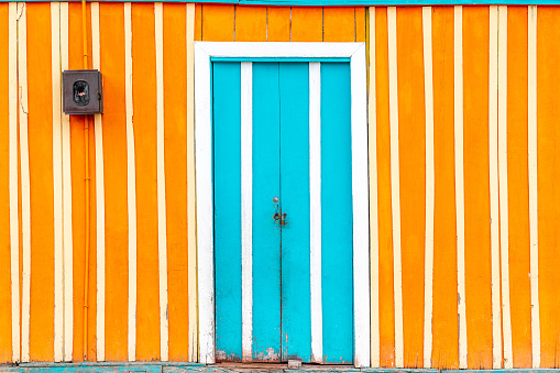 Orange stripy  wall facade and a blue  door in the city centre of Tolima, Colombia