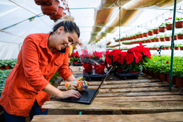 istock Female florist talking on the phone with customer while using laptop 1357666284