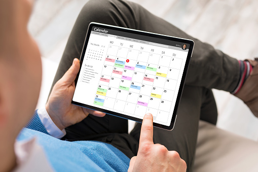 Man checking his schedule by using calendar app on tablet computer