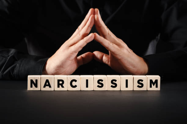 Man with clasped hands with the word narcissism. Personal ego or selfishness concept. Man with clasped hands with the word narcissism on wooden blocks. Personal ego or selfishness concept. vanity stock pictures, royalty-free photos & images