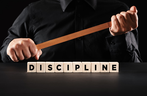 Discipline in business workplace or in school classroom concept. Male teacher or boss holds a wooden stick with the word discipline.