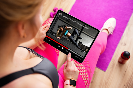 Woman getting ready for a workout and watching workout video on tablet computer