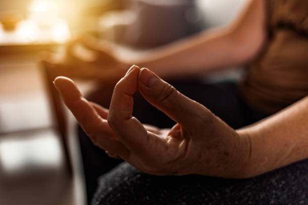 Serene elderly woman meditating at home Calm elderly woman relaxing on couch sitting with fingers makes mudra gesture meditating mudra stock pictures, royalty-free photos & images
