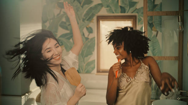 istock Feeling fabulous. Diverse friends enjoying morning bathroom routine and having fun in front of mirror. Crazy dance moves 1357673144