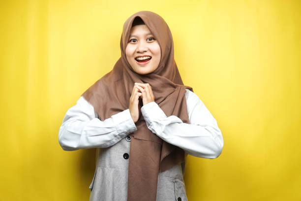 Beautiful young asian muslim woman shocked, surprised, wow expression, isolated on yellow background stock photo