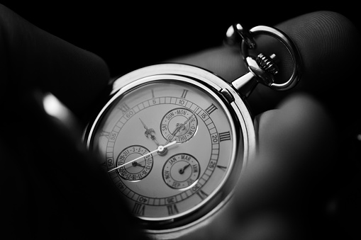 Hand holding a luxury pocket watch. Extreme close up, black and white.