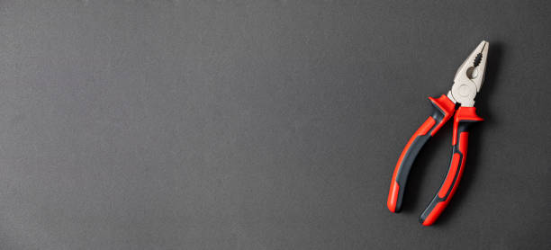 istock Pliers in red and black colored on a black background with blank text space 1357678424