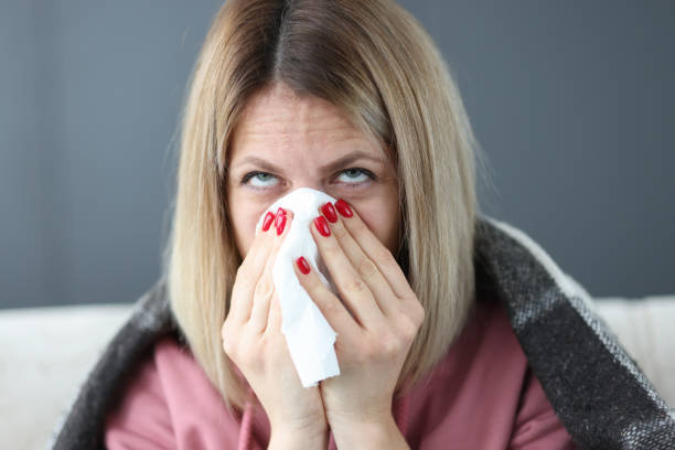 istock Sick woman blows her nose into handkerchief. 1357680050