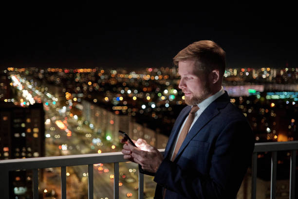 istock Young successful businessman with smartphone texting on balcony 1357681581