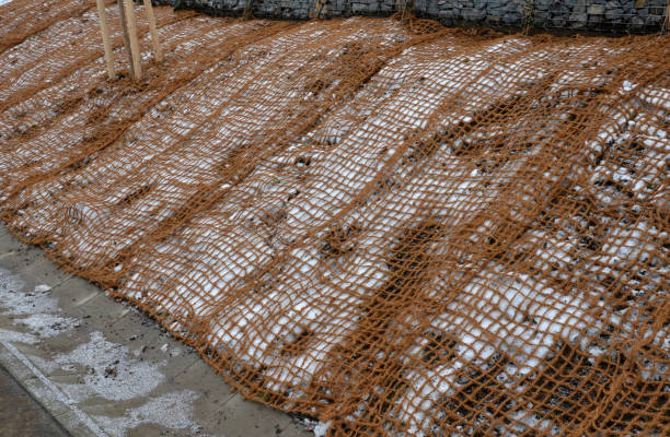 temporary covering of the lawn sowing with textiles to ensure a large slope against erosion. using brown jute fabric stabilizing coconut net for steep slopes. in heavy rain the soil does not leach out, leaching, pins cubrimiento temporal de la siembra de césped con textiles para asegurar una gran pendiente contra la erosión. utilizando tela de yute marrón estabilizando la red de coco para pendientes pronunciadas. bajo fuertes lluvias, el suelo no se filtra