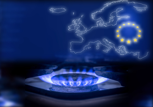 La llama azul de una estufa de gas en la oscuridad. Quemador de gas en el fondo del mapa y la bandera de la Unión Europea. El concepto de consumo de gas en Europa photo