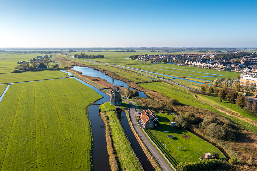 Typical Dutch polder landscape with a typical Dutch sky. An old windmill is in the foreground. Drone shot. panning shot.